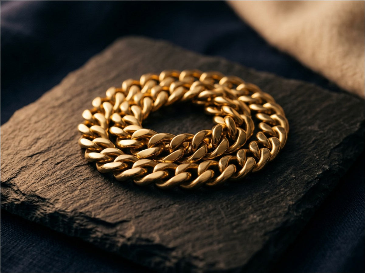 A coiled gold curb chain resting on a slate tile